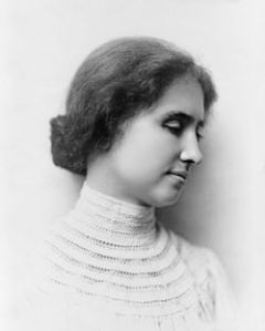 Photographie en noir et blanc d'Helen Keller de profil. Ses cheveux sont noués en chignon et elle porte un vêtement blanc à col montant