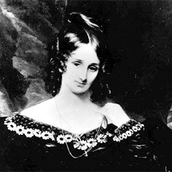 Portrait de Mary Shelley portant une robe noire au décoleté décoré de fleurs claires. Elle penche légèrement la tête et porte ses cheveux sombres en boucles anglaises