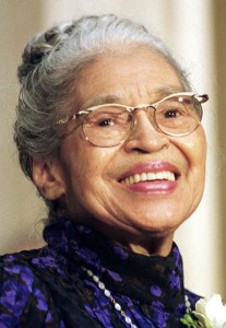 Photographie de Rosa Parks âgée, ses cheveux grisonnants retenus en chignon. Elle porte des lunettes et a un large sourire.