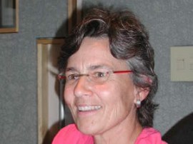 Photographie d'Ann Bancroft souriante. Elle a les cheveux sombres courts et porte des lunettes.