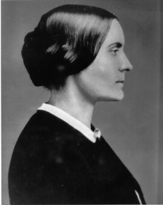 Photographie en noir et blanc de Susan B Anthony prise de profil. Elle porte une robe sombre et ses cheveux bruns sont noués en chignon.