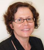 Cette image est une photographie d'Anne-Marie Lagrange. Elle porte une veste noire et des lunettes. Ses cheveux chatains sont coupés courts ; elle sourit.