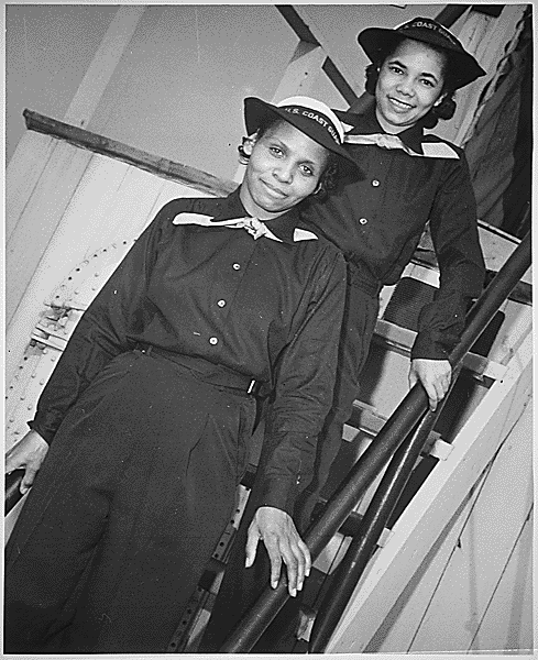 Cette photographie en noir et blanc montre deux femmes noires souriantes en uniforme de coast guard des Etats-Unis, debout sur un escalier à bord d'un bateau. Olivia Hooker est devant, Aileen Anita Cooks derrière.