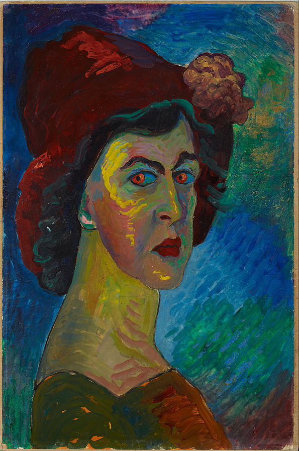 Cette image est un autoportrait de Marianne von Werefkin ; elle est représentée de profil, regardant vers le spectateur. Le tableau est dans des tons bleus, verts et rouges. Elle porte un chapeau rouge avec une fleur, et ce rouge est rappelé dans ses yeux, ses lèvres et sa robe.