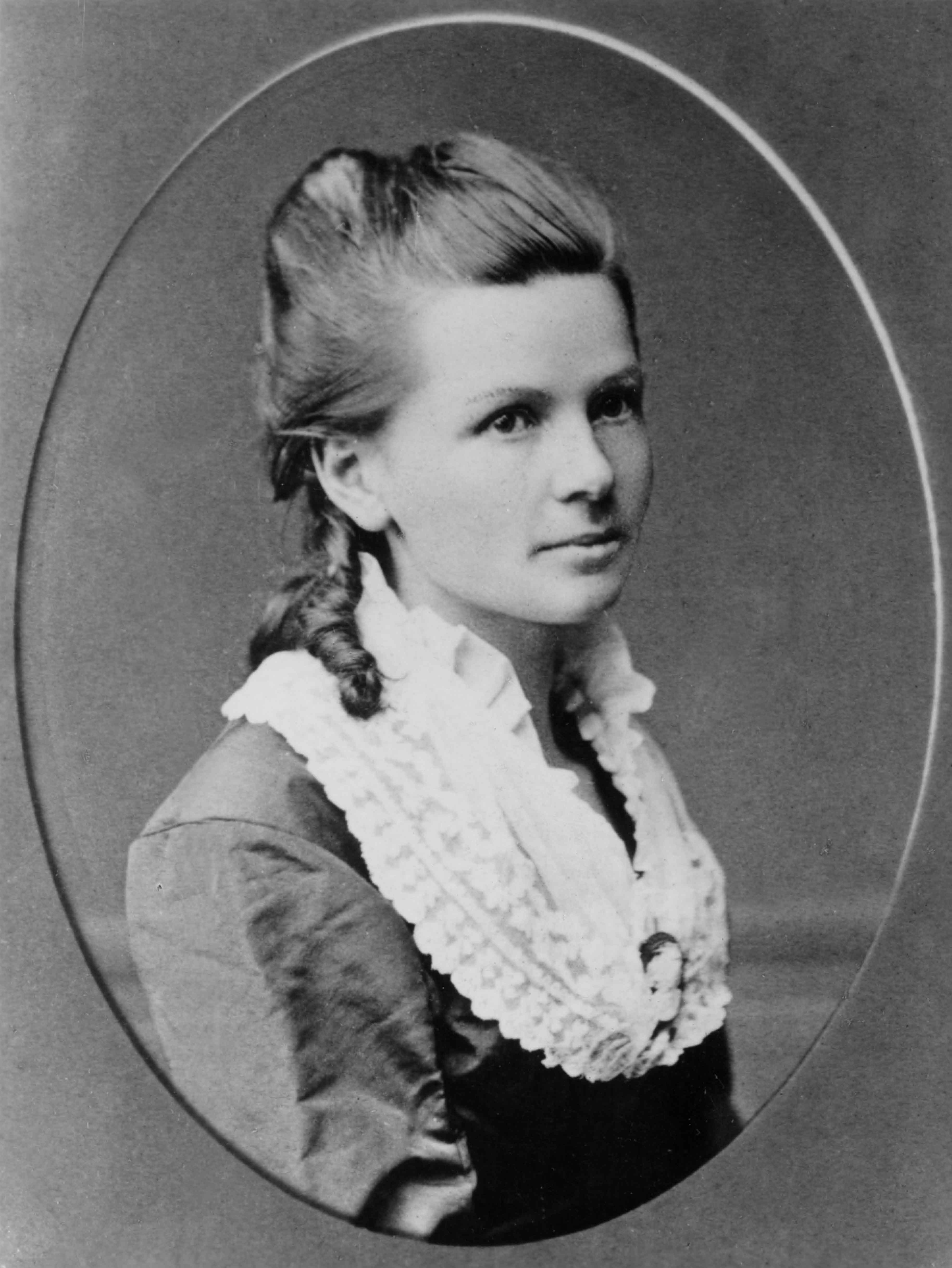 Cette photographie en noir et blanc est  un portrait de Bertha Benz dans un cadre ovale. La jeune fille porte une veste sombre avec un large col blanc de dentelle ; ses cheveux sont coiffés en mèches anglaises.
