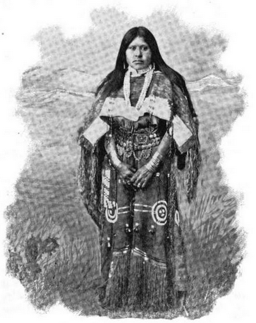 Cette image en noir et blanc montre Chipeta en pied. Elle est vêtue de vêtements traditionnels Utes, avec une jupe à frange et une veste aux manches amples. Elle porte ses longs cheveux lisses libres, jusqu'aux épaules.