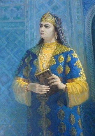 Cette illustration montre Nadira, vêtue d'une robe bleue et jaune. Elle porte une couronne, un collier avec de nombreux rangs de perles, des bracelets et des bagues. Un voile recouvre ses cheveux. Elle tient un livre entre ses deux mains.