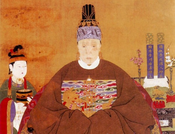 Cette image représente une femme noble de la dynastie Ming, portant des vêtements traditionnels amples, longs et marron, ainsi qu'une coiffe et des boucles d'oreille.