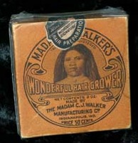 Cette photographie montre l'emballage d'un produit de la Madam CJ Walker Company. L'emballage orange montre un portrait de Madam CJ Walker, le nom de la compagnie et la mention "Wonderful Hair Grower"