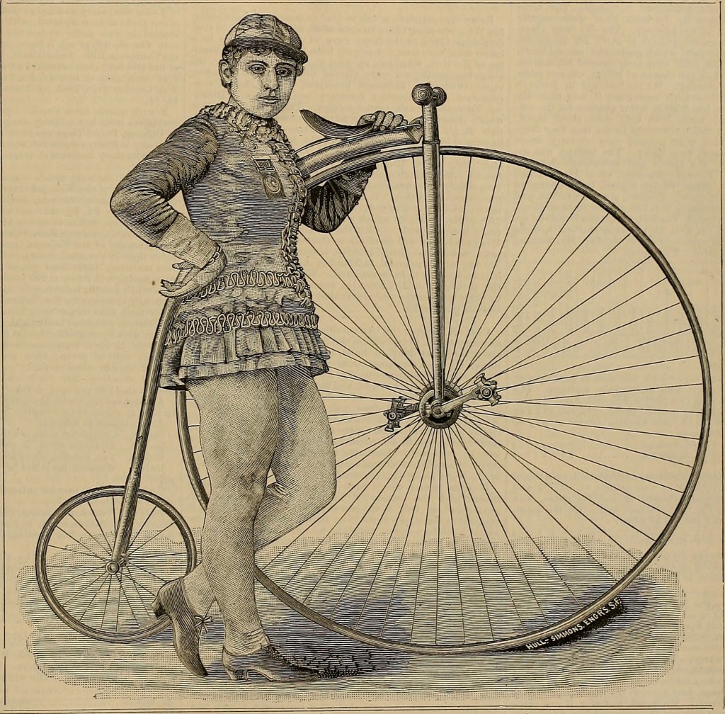 Cette gravure montre Louise Armaindo debout devant son grand bi, dont la roue avant lui arrive aux épaules et la roue arrière aux genoux. Elle a la main gauche posée sur la selle, la main droite sur sa hanche.